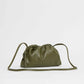 The olive green Mini Cloud Clutch by Mansur Gavriel is crafted from Italian lambskin with gathered, ruched top details and a long, thin strap, shown against a plain light background.