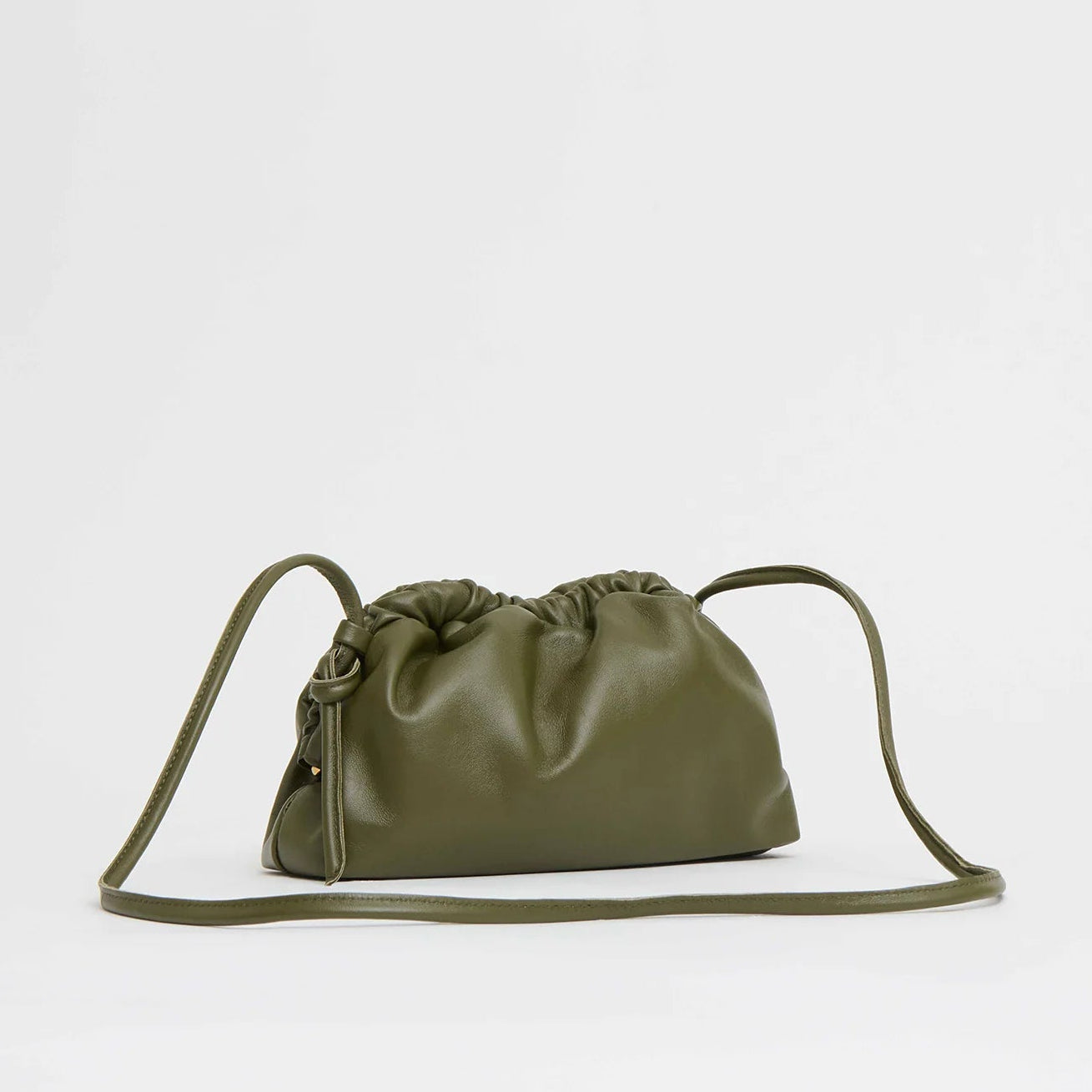 The olive green Mini Cloud Clutch by Mansur Gavriel is crafted from Italian lambskin with gathered, ruched top details and a long, thin strap, shown against a plain light background.