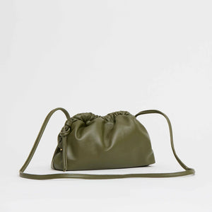 The olive green Mini Cloud Clutch by Mansur Gavriel is crafted from Italian lambskin with gathered, ruched top details and a long, thin strap, shown against a plain light background.