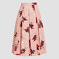 The Erdem Pleated Abstract Rose Skirt, a high-waisted pink midi skirt with red abstract rose pleats, is showcased against a plain light background.