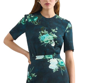 Model in Erdem’s Short Sleeve Abstract Rose Top, featuring dark blue fabric with green and white abstract roses, short sleeves, and a fitted waist; shown from shoulders to mid-thigh.