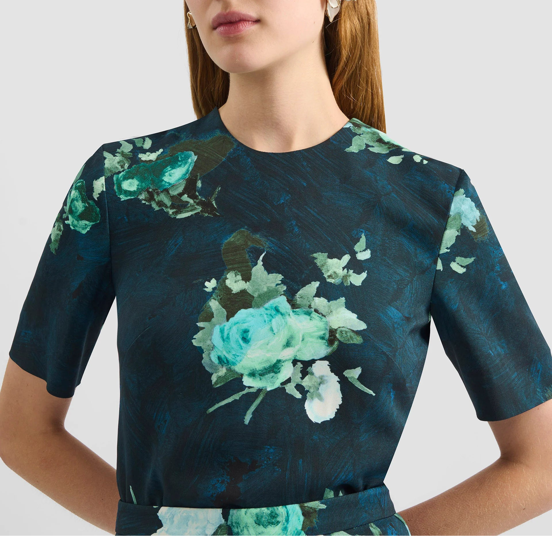 A woman wears the Erdem Short Sleeve Abstract Rose Top, featuring a modern rose pattern, against a plain background.