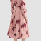 A woman is seen from the back wearing Erdem’s Pleated Abstract Rose Skirt with a coordinating long-sleeve, belted top, and textured black flat shoes.