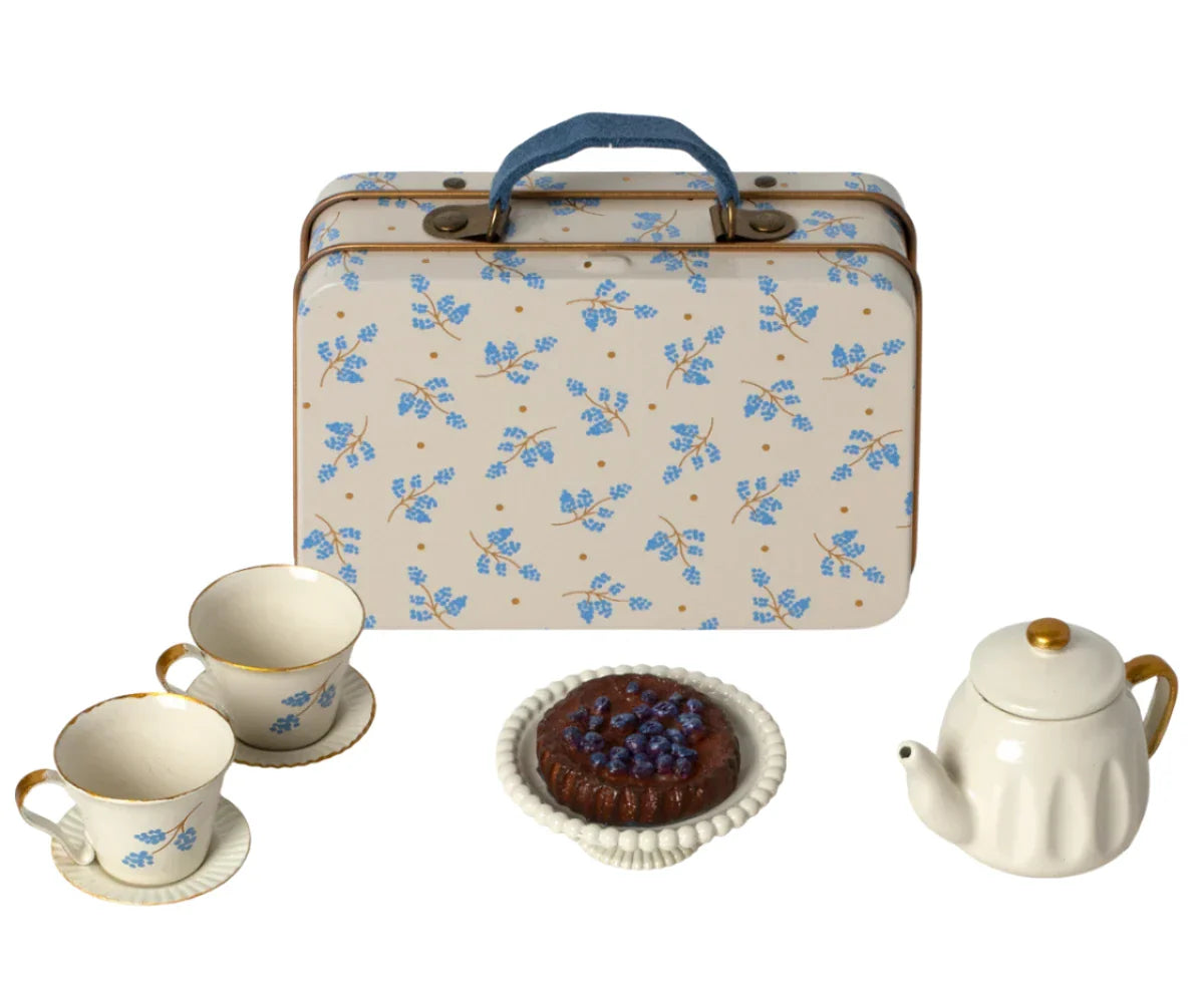 The Maileg Afternoon Treat, Mouse - Blue Madelaine, featuring a charming blue floral pattern reminiscent of Maileg's signature designs, includes a vintage tin suitcase elegantly displayed with two teacups on saucers, a teapot, and a small cake on a plate.