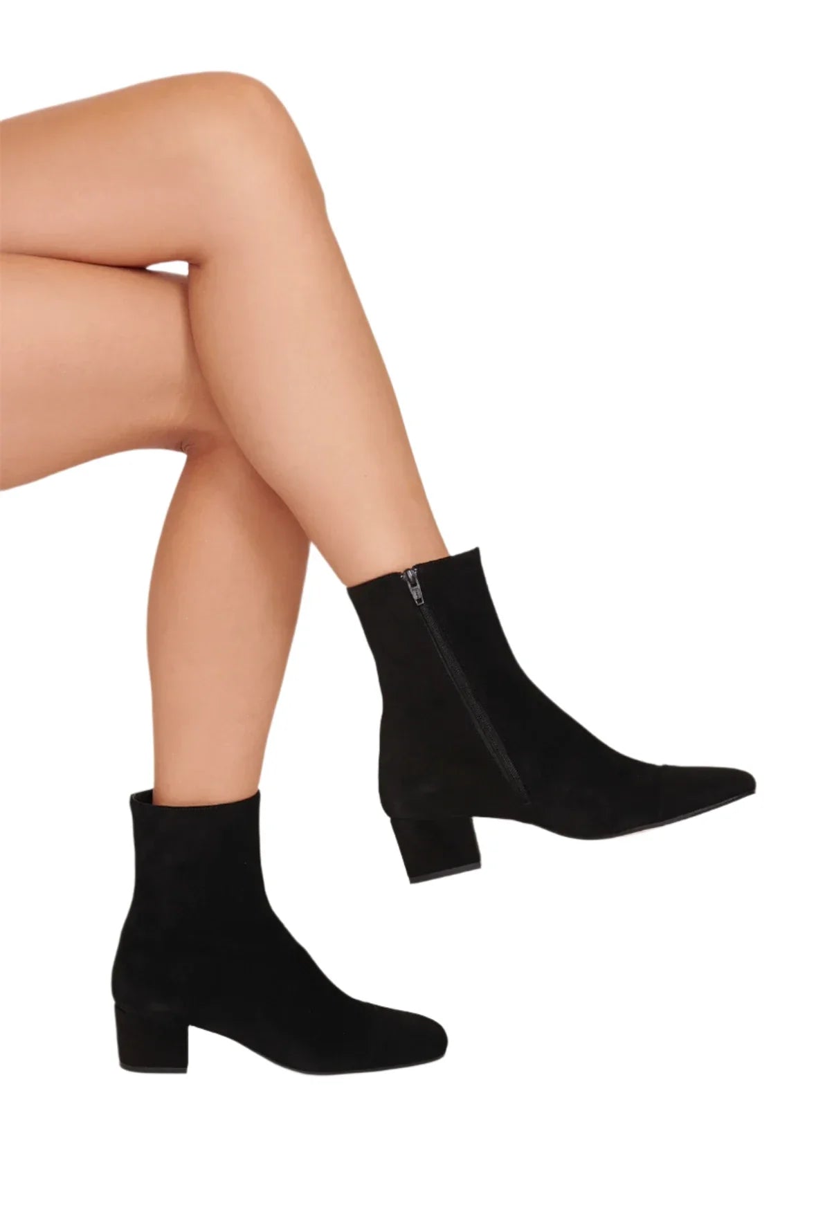 A person is showcasing the Staud Aimee Short Boot, featuring a sleek black suede finish with a block heel and round-toe design, set against a white background.