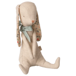 The Maileg Bunny Albin, by Maileg, is crafted from soft linen quality and features floral-patterned ears, a green fabric neck bow, and simple stitched facial features. This charming rabbit doll sits upright and has magnets in its hands for added versatility.