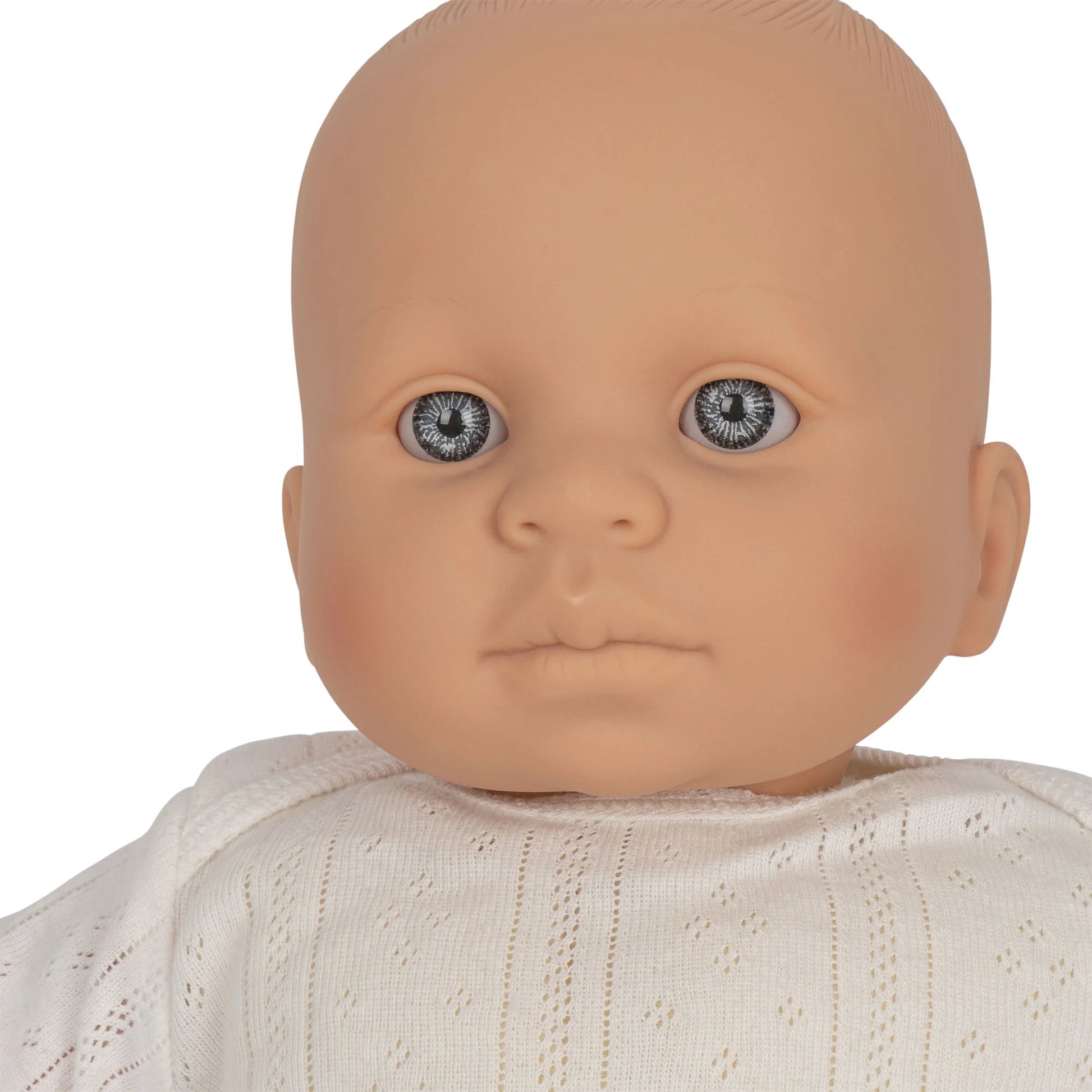 A close-up of Konges Slojd Alfie the Doll, featuring a neutral expression and wearing an outfit made from organic cotton and recycled polyester.