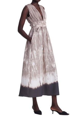 A person wearing an Altuzarra Fiona dress that exudes modern femininity, this sleeveless v-neck design with pleats features a white and grey pattern and transitions into a solid grey at the bottom hem. Craft