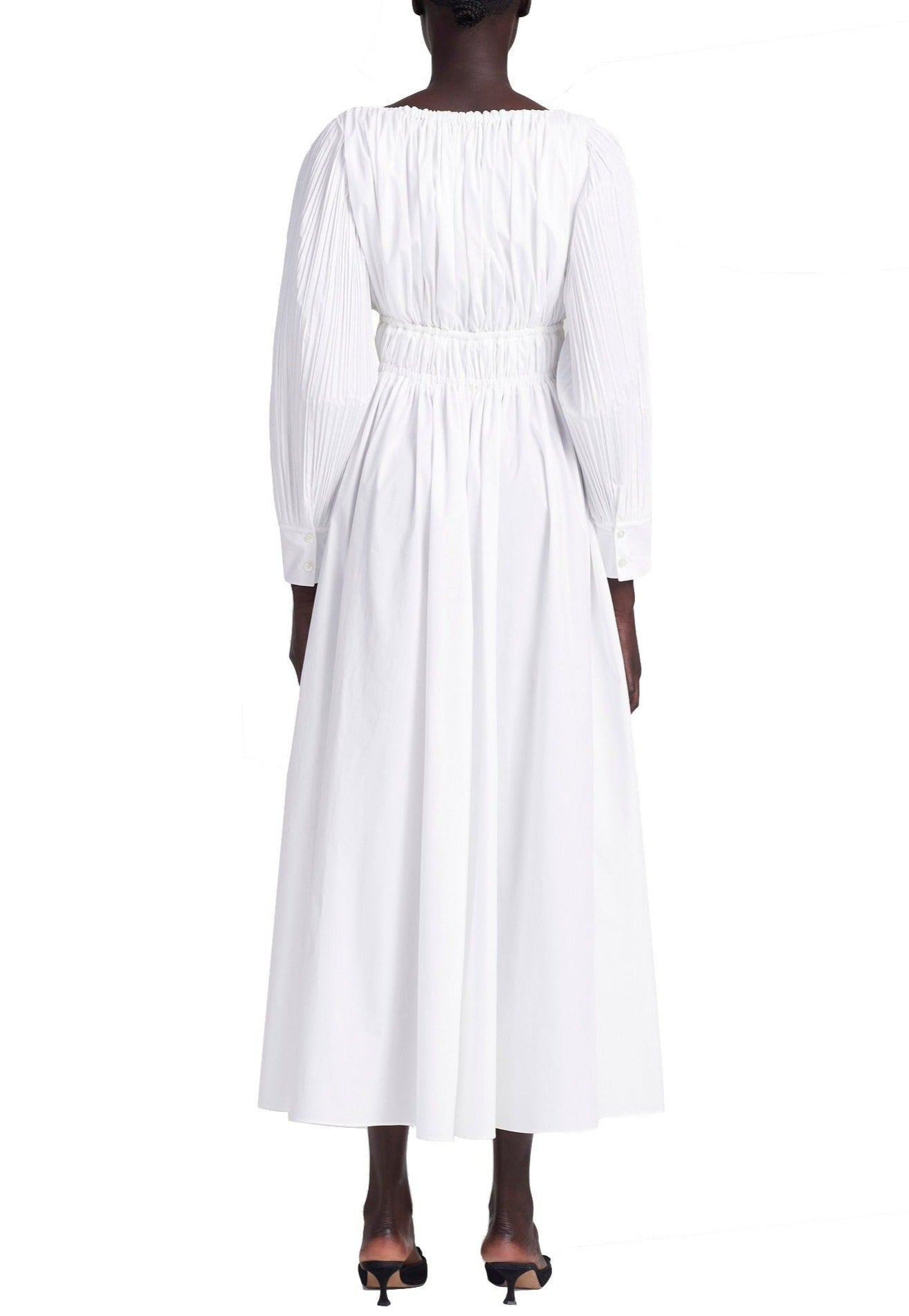 Woman wearing a white Altuzarra Kathleen Optic White Dress with a maxi silhouette and long sleeves, standing against a white background.