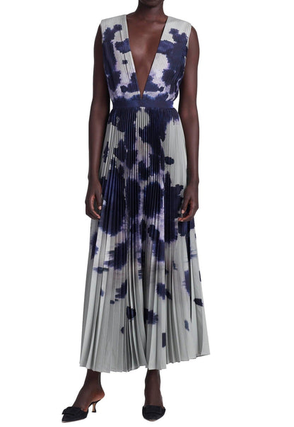 Someone is wearing Altuzarra's sleeveless Pamela Dress, featuring a deep V-neck, pleated midi style, and blue and white abstract pattern, paired with black heels for an elegant look.