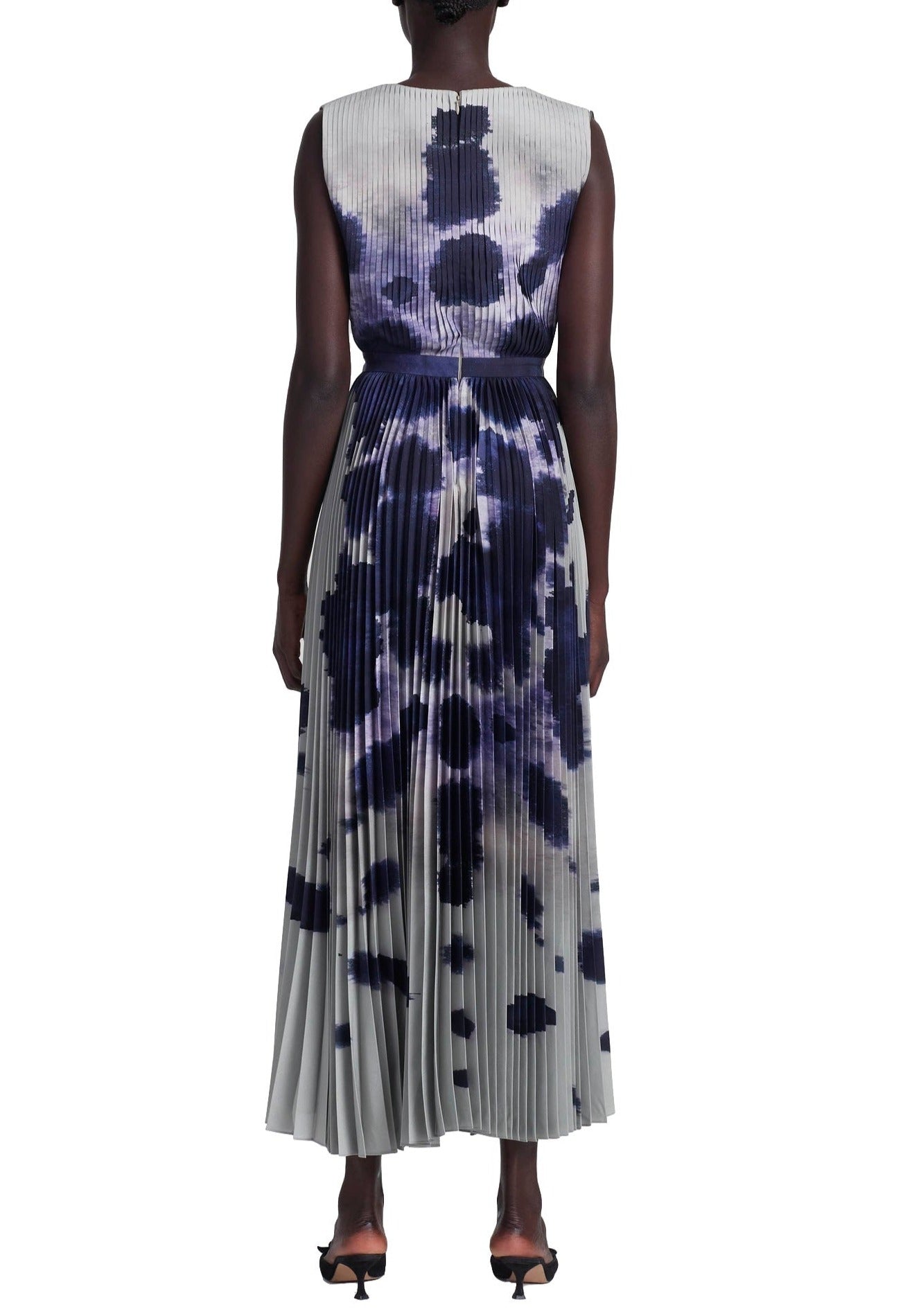 Back view of a person wearing an Altuzarra Pamela Dress, a sleeveless, ankle-length piece with a pleated skirt, featuring an abstract black and white pattern with hints of purple.