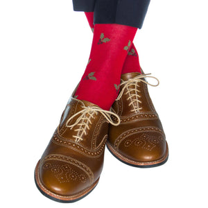 A person sports brown dress shoes with beige laces and Dapper Classics Red with Burgundy Berry and Pine Green Holly Wool Sock Linked-Toe Mid-Calf, pants slightly raised above the ankles.