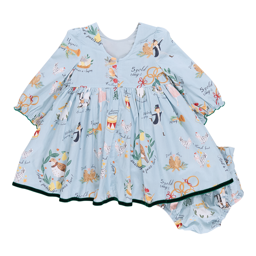 A Pink Chicken Baby Girl Amma Dress in light blue, featuring a festive pattern of animals and musical instruments reminiscent of the 12 Days of Christmas, comes with matching bloomers.