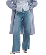 Person wearing Rag & Bone Flexi Andi Full Wide high-waisted wide-leg blue jeans, a blue and white striped shirt, a matching long striped coat, and silver ballet flats.