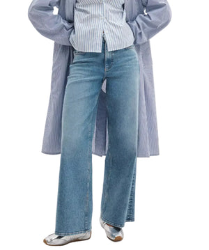 Person wearing Rag & Bone Flexi Andi Full Wide high-waisted wide-leg blue jeans, a blue and white striped shirt, a matching long striped coat, and silver ballet flats.