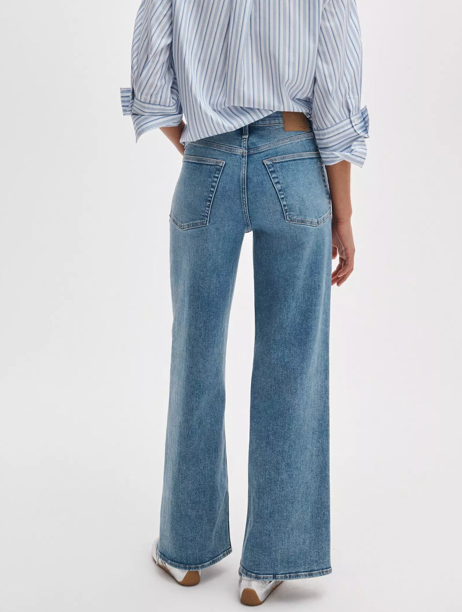 Person wearing a blue and white striped shirt and Rag & Bone Flexi Andi Full Wide high-waisted denim jeans, shown from the back against a plain background.
