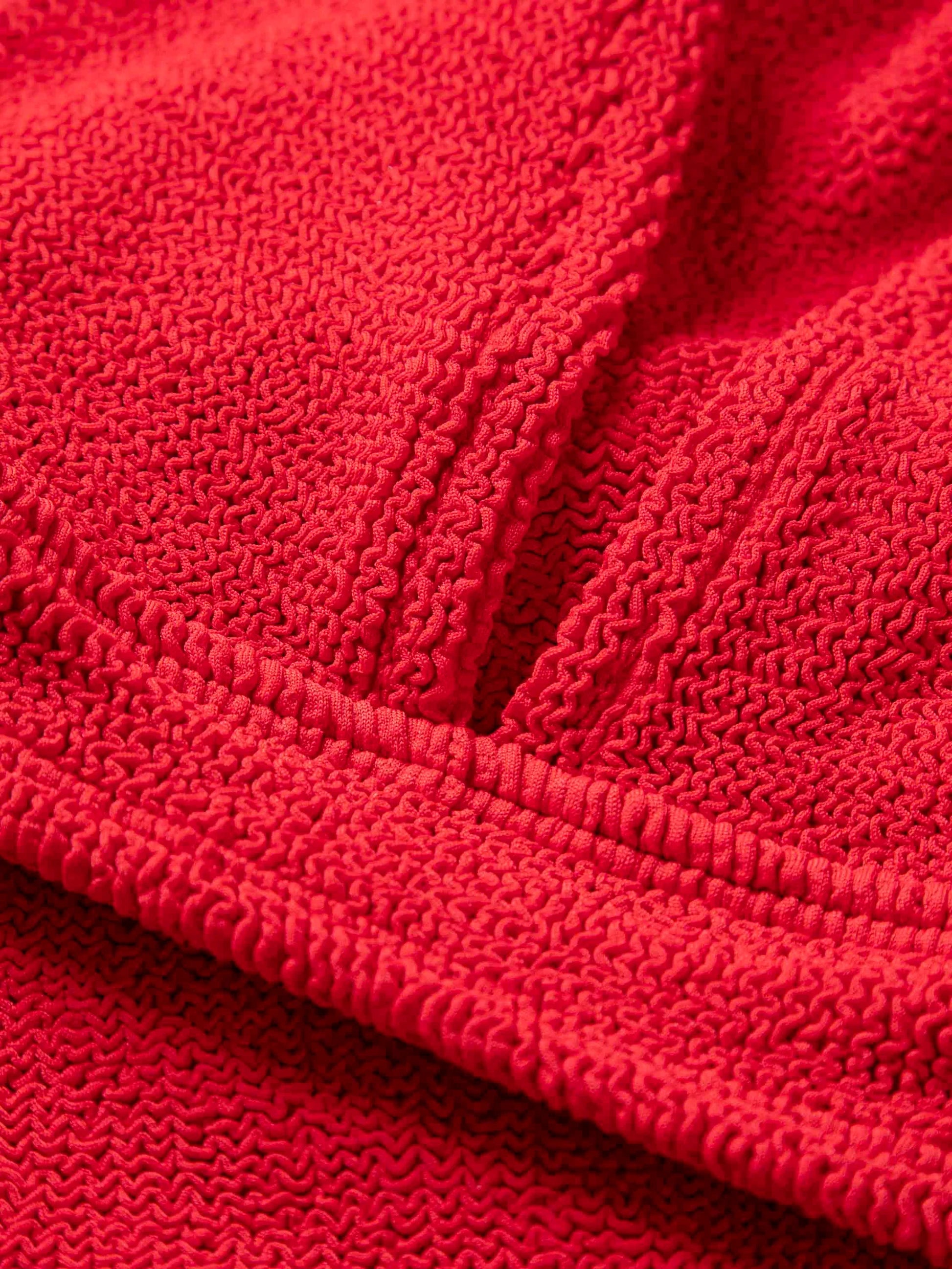 Close-up of textured red terry cloth with visible stitching and seams, ideal for crafting the Angel Bikini by Hunza G, designed as supportive one size swimwear.