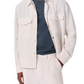 A man wears the Rag & Bone Angus Linen Shirt Jacket, a military-inspired cream button-up with flap pockets, layered over a dark textured shirt and paired with matching cream pants.