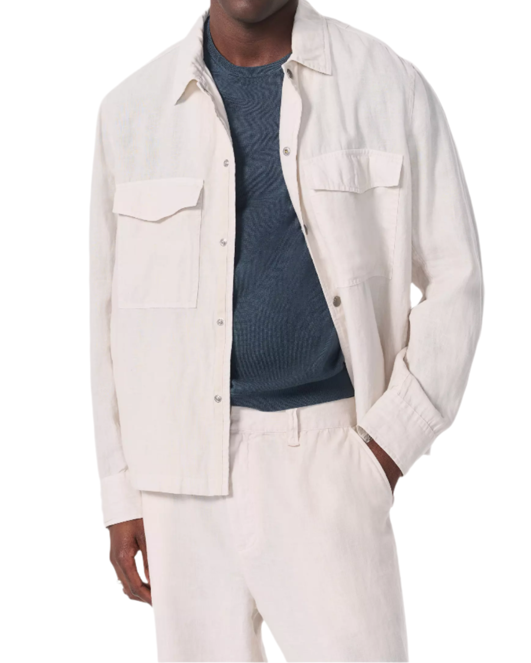 A man wears the Rag & Bone Angus Linen Shirt Jacket, a military-inspired cream button-up with flap pockets, layered over a dark textured shirt and paired with matching cream pants.