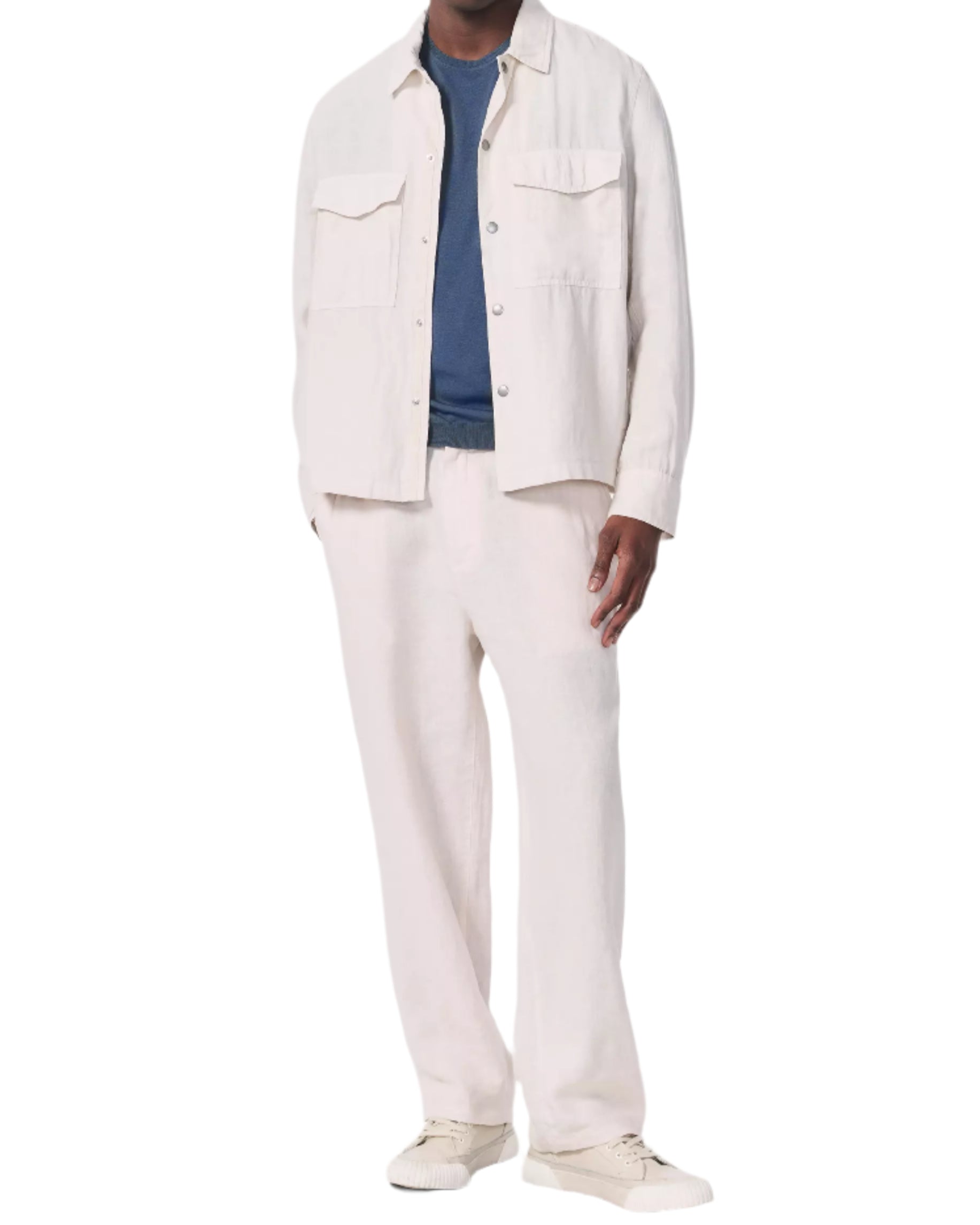 A man wearing the Angus Linen Shirt Jacket by Rag & Bone with matching pants, a blue t-shirt, and beige sneakers stands against a white background.