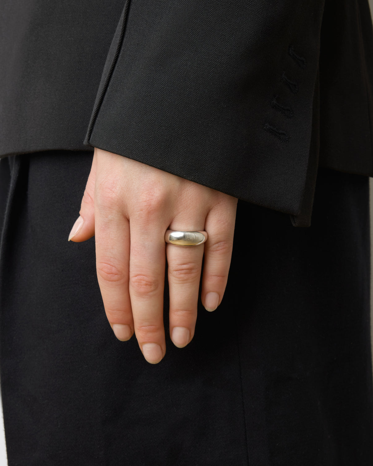 A hand wearing the Lie Studio Anna Ring in sterling silver rests by the side, partially covered by a black suit jacket sleeve.