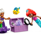 In the LEGO® Disney™ Ariel's Crystal Cavern playset from Legos - Toyhouse, two LEGO figures explore a treasure chest. One of the figures is holding a magnifying glass, while a small fish hovers above. The chest features translucent purple gems reminiscent of Ariel's adventures.