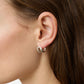 Close-up of a woman's ear with long brown hair, wearing a small, shiny sterling silver hoop Asta Earring from Lie Studio, highlighting its refined silhouette.