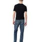 A person faces away against a plain light background, wearing the Rag & Bone Aulton Knit Tee in black with blue jeans.