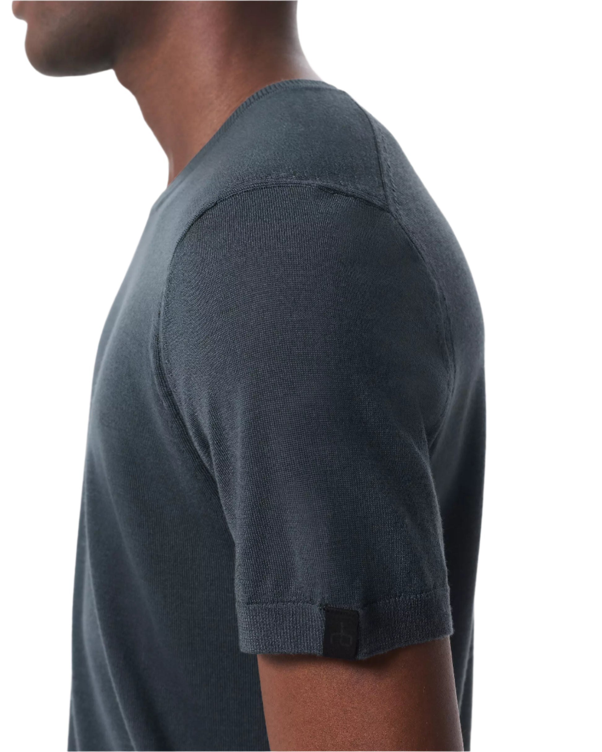 A person with a slim profile is shown from the side wearing the Rag & Bone Aulton Knit Tee, a short-sleeve dark gray shirt, against a white background.