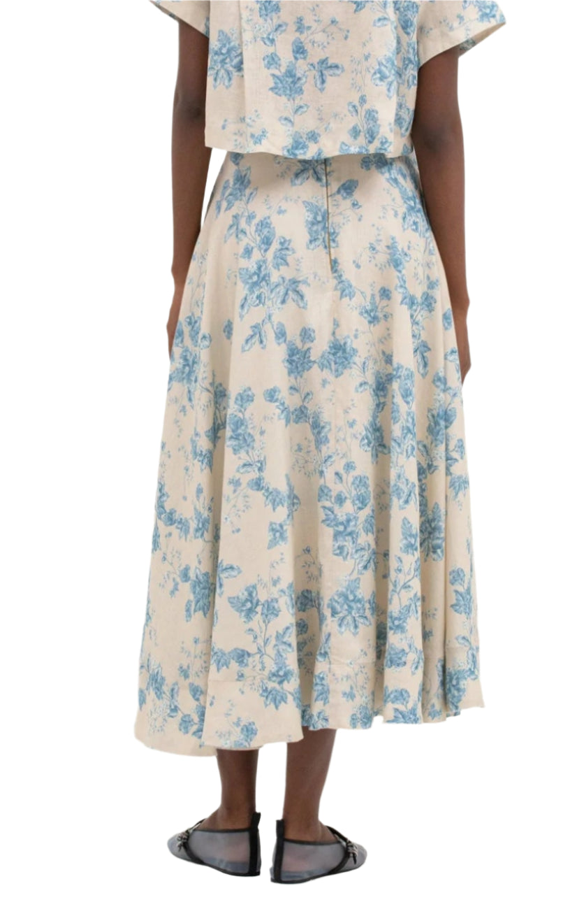 Wearing an Agua by Aguabendita Bergamota Skirt with a matching floral beige and blue top, featuring a long cotton linen design and concealed zip fastening. Black sandals visible.