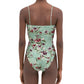 Someone wears the Durazno Embroidered One Piece by Agua By Aguabendita, a green floral swimsuit with thin shoulder straps and a low-cut back, crafted from grecycled polyester and shown from behind.