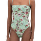 A person wears the Durazno Embroidered One Piece by Agua By Aguabendita, featuring a floral pattern and thin shoulder straps, made from recycled polyester, standing against a white background.