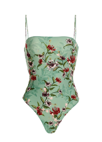The Durazno Embroidered One Piece by Agua By Aguabendita is a mint green swimsuit with thin straps, made from recycled polyester, and features red, purple, and green floral embroidery.
