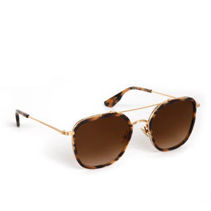 The Austin Sunglasses by Krewe feature gold metal aviator frames, brown tortoiseshell accents, and dark brown lenses—designed to flatter various face shapes. Shown on a white background.