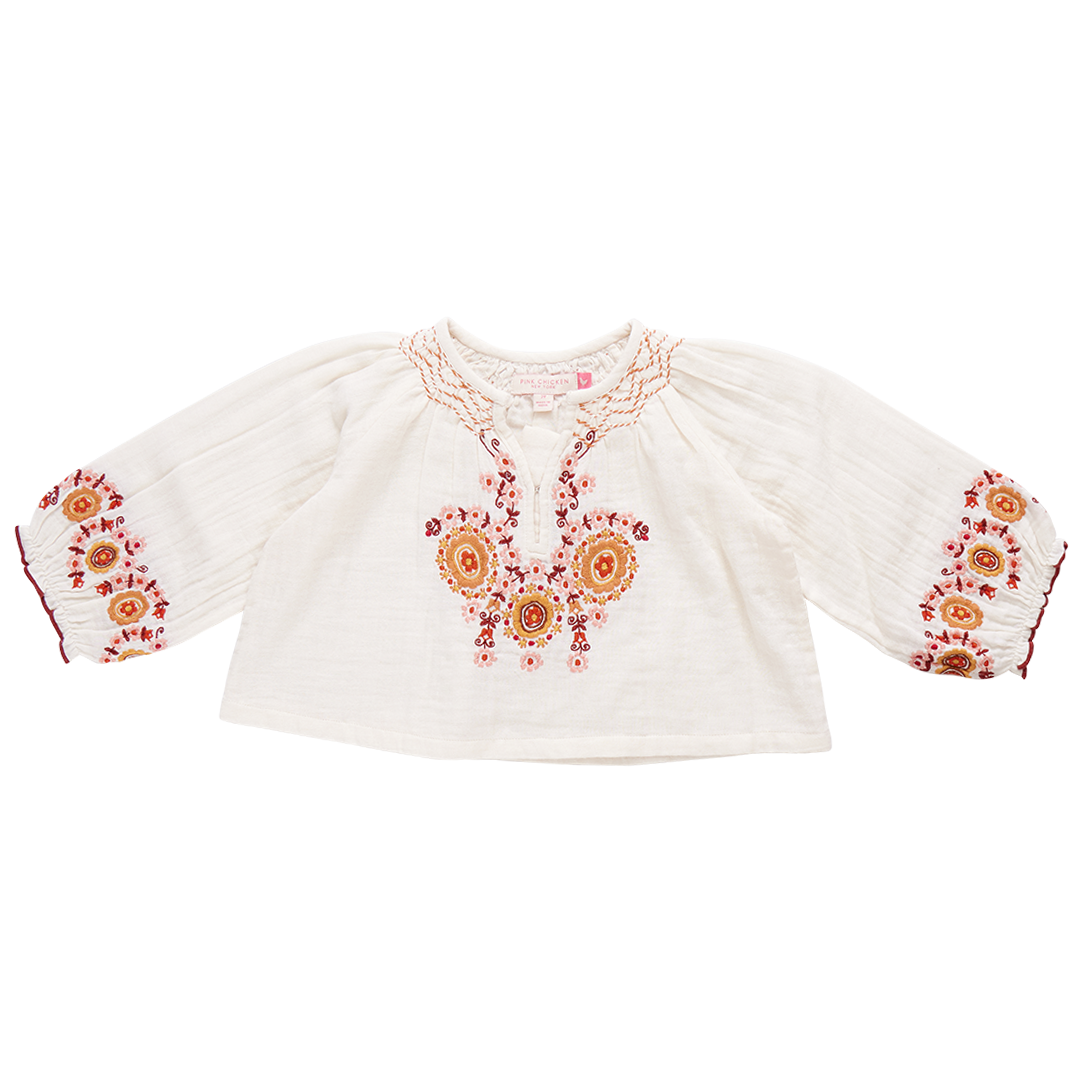 A white, long-sleeve Pink Chicken Girls' Ava Top in toddler size, featuring vibrant orange and pink floral harvest embroidery on the chest and cuffs, perfect for a touch of boho fashion.