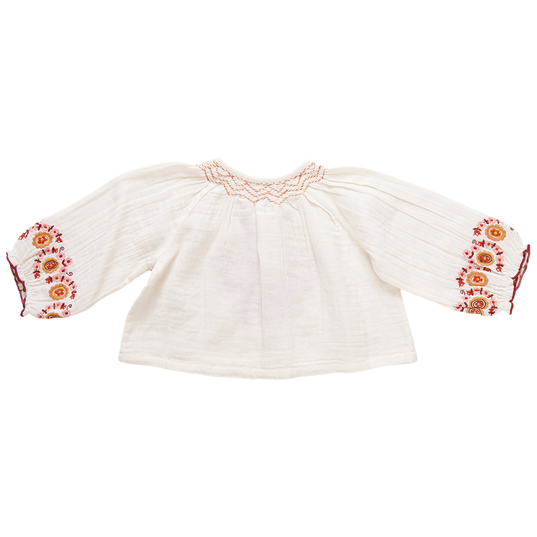 A white long-sleeve, loose-fitting Pink Chicken Girls' Ava Top by Pink Chicken, featuring colorful embroidered patterns on the chest and cuffs, perfect for Boho Fashion enthusiasts.