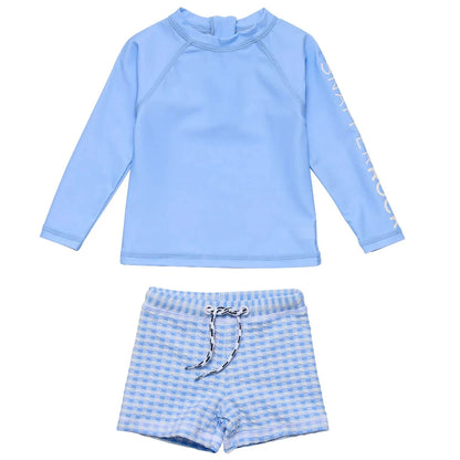 The Snapper Rock Baby Boys' Swaside Blue LS Set includes a long sleeve light blue rash top and blue gingham swim shorts with an elastic waistband and drawstring for comfort.
