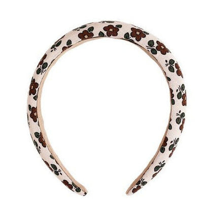 Add style to your outfit with the Rylee & Cru Padded Headband, featuring a white base adorned with brown flowers and green leaves.