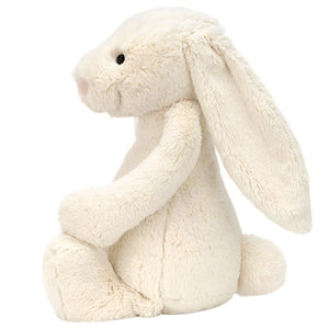 A Jellycat Bashful Bunny Cream, Huge with long ears is sitting upright against a white background. This soft bunny toy, with its plush beige fur, makes for an adorable stuffed animal companion.