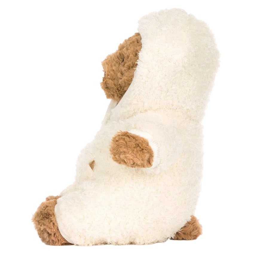 A Jellycat teddy bear in a fluffy white Bartholomew Bear All-in-One Outfit sits upright in side profile, ready to lounge for hibernation season against a plain white background.
