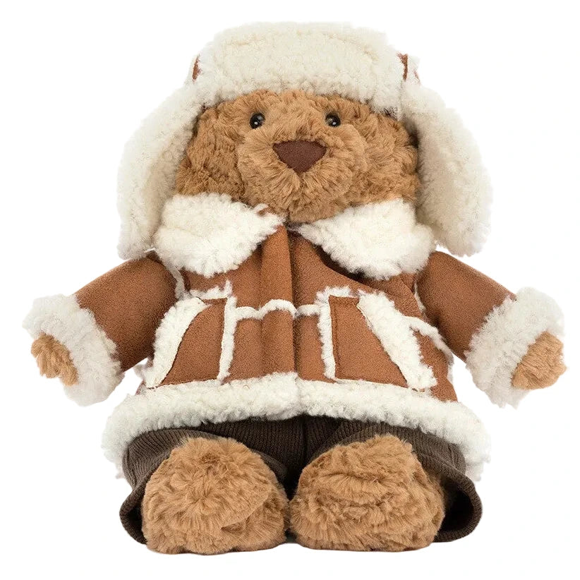 Jellycat Bartholomew Bear ‘Alpine’ wearing a shearling-lined aviator hat and matching coat with brown trousers.