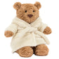 A Jellycat Bartholomew Bear Bathrobe plush, featuring a brown bear in a soft white robe, sits upright against a plain background.