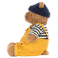 Jellycat's Bartholomew Bear Seafarer Outfit features a plush bear in a navy knit hat, black-and-white striped shirt, and yellow overalls, sitting upright in profile—ready for his next adventure.