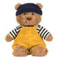 Bartholomew Bear Seafarer Outfit by Jellycat features a plush bear in a navy knit hat, black and white striped shirt, and yellow overalls, sitting against a white background, ready for seaside adventures.