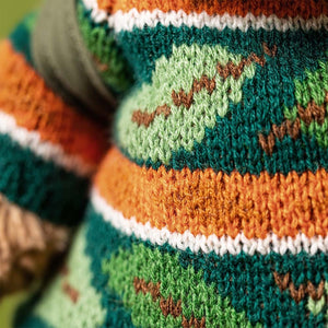 Close-up of a knitted sweater with green, orange, white, and brown zigzag stripes—perfect for pairing with your Jellycat Bartholomew Bear Hiking Outfit.