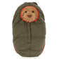 A Bartholomew Bear face peeks out from the hood of Jellycat's olive green, puffy Bartholomew Bear Hiking Outfit baby bunting with orange trim.