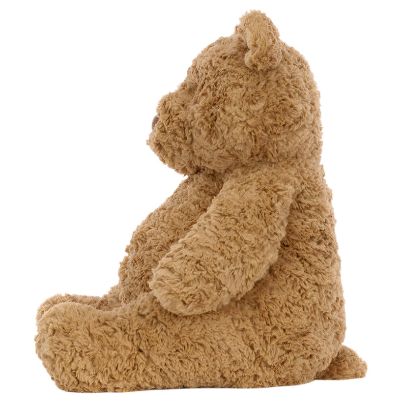 Side view of Jellycat’s Bartholomew Bear, Medium—a brown teddy with a fluffy fudge tummy—sitting upright against a plain white background, making it the perfect bedtime buddy.