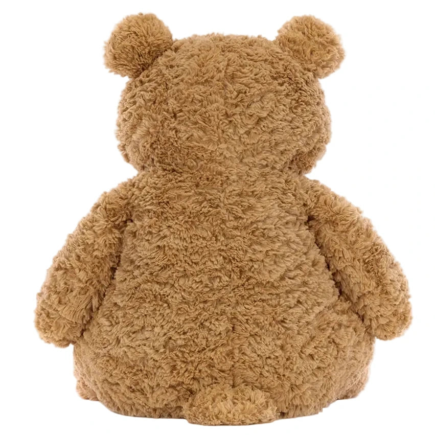 The Jellycat Bartholomew Bear Huge, a brown, fluffy teddy bear, is pictured sitting with its back to the viewer, showing off its round ears and short tail.