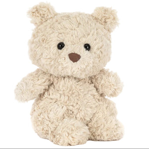 A Bartholomew Bear Junior teddy bear from Jellycat, featuring beige fluffy fur, black eyes, and a brown nose, sits upright against a white background.