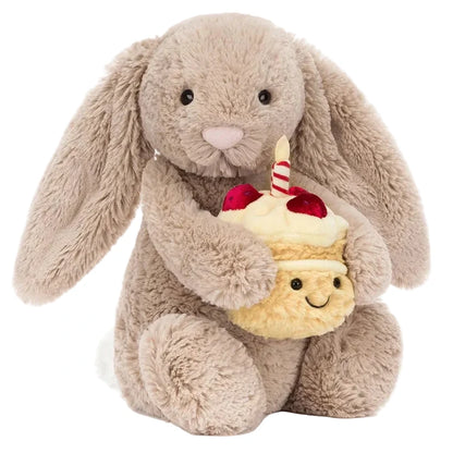 The Jellycat Bashful Beige Bunny 'Birthday' holds a plush cupcake topped with a candle and cherries—a delightful birthday gift for any celebration.